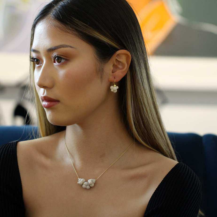 Model wears atelier luz 18k yellow gold porcelain cloud earrings necklace designyard contemporary jewellery gallery dublin ireland