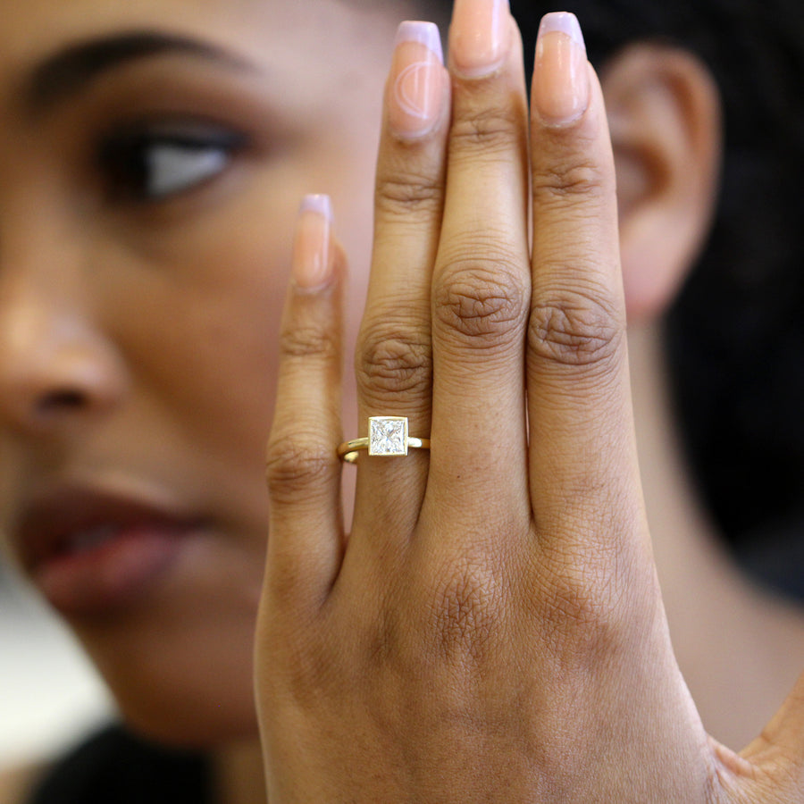 Model wears gold Mēdēəm Bezəl princess cut diamond ring by Ronan Campbell at designyard contemporary jewellery gallery dublin ireland